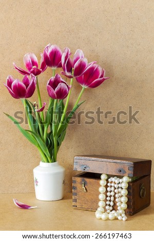 Bright purple flowers in a white vase tulips and wooden chest with pearls