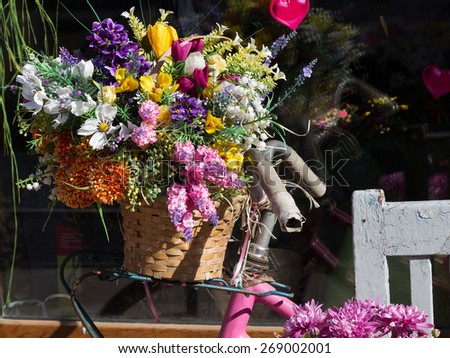 Original ornamental decoration bouquet of spring flowers in a wooden box and iron bucket and retro bike. Flowers in bright sunlight on a contrasting background of a contrasting shade.