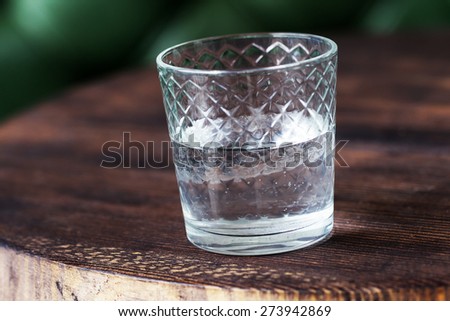 An authentic glass of drinking water on the old wooden table. Full-time atmospheric lighting, fashionable trendy spot soft focus. Preparation for creative design.