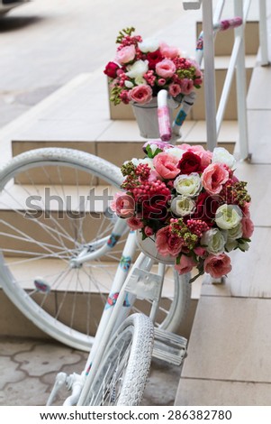 Creative bouquet of colorful artificial flowers on old white bicycle. Selective focus and space in the zone blurring compositions for the production of advertising and text.