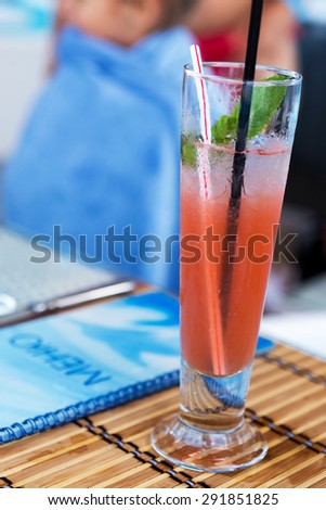 Light alcoholic drink with watermelon juice and ice in the glass. Blur beautiful bouquet of flowers. Soft selective focus.