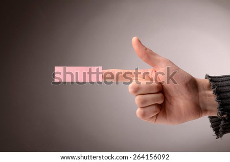 Male hand making a pistol with a sticky note on the index finger