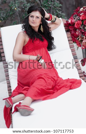 Young beautiful smiling girl resting on sofa in summer cafe