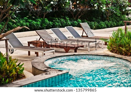 Beach chairs near swimming pool in tropical resort , Thailand.