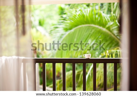 Coffee in a cup on balcony with nature and palm