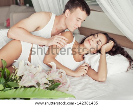 Young man awake his beautiful girlfriend and giving her a bouquet of flowers