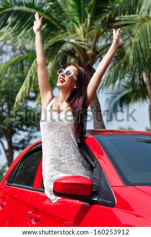 Summer vacation car road trip freedom concept. Happy woman cheering joyful during holiday travel in red car.