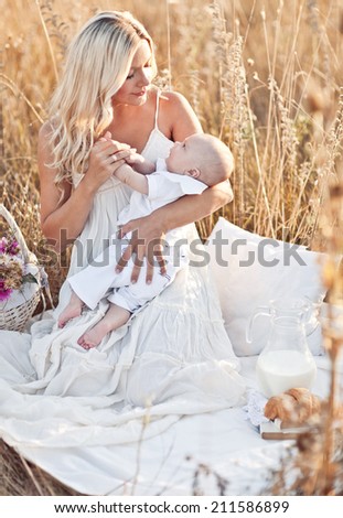 Happy family on sunset. Mother in white dress with baby in nature