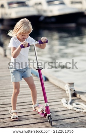 Little girl on scooter near the sea