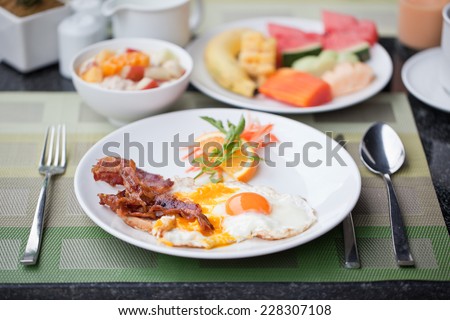 Hotel breakfast. Fried eggs with bacon and fruit