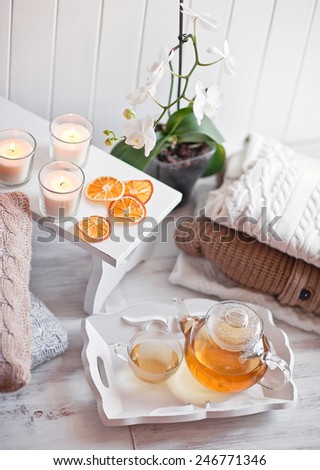 Tea-tray with hot grass drink, knitting clothes, dry oranges, candles and flowers. Winter mood. Cozy style