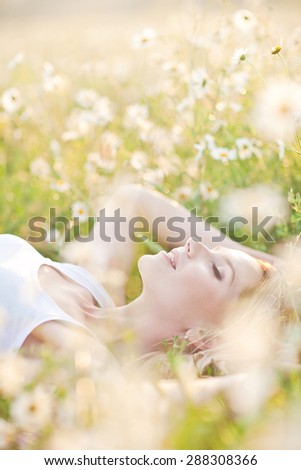Beautiful woman enjoying daisy field, nice female lying down in meadow of flowers, pretty girl relaxing outdoor, having fun, holding plant, happy young lady dansing in spring green nature