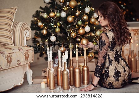 Christmas Candles. Happy Surprised Woman Posing Near Christmas Tree at home.