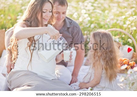 happy little girl drinking milk in the camomile field. picnic