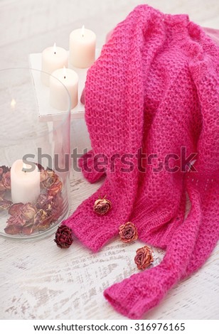 White wood stool with candles, dry roses and pink wool sweater, pullover. Autumn mood.