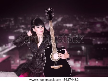 young girl with a guitar on a roof of a high-rise building