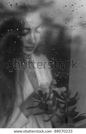 closeup beauty portrait of blonde woman blowing from behind a wet window