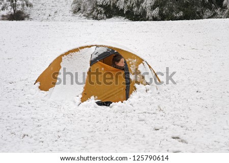 a girl looking out of the tent and snowing outside