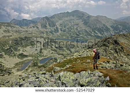 Man trekking in mountain, view above Bucura Lake, Viorica and Florica Lake and Peleaga Peak, the highest peak in Retezat National Park, Romania