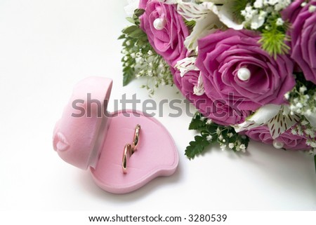 Wedding rings in a pink box of the form of heart near to a bouquet of the bride