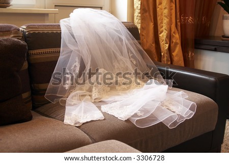 The clothes prepared for the bride lay on a sofa near a window