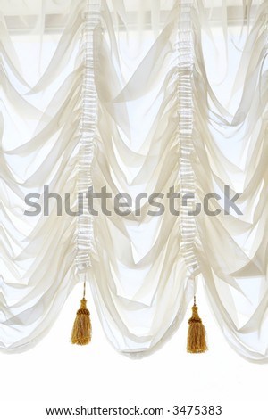 At a window the white curtain with folds passing heavenly light hangs