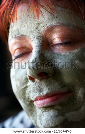 Cosmetic mask of green clay on a leather of the face of the woman
