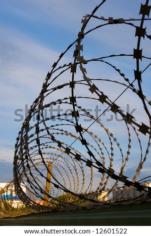 The spiral of barbed wire protects a private property from climb over  a fence