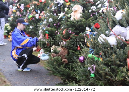 NEWTOWN, CT., USA, DEC 16, 2012: Sandy Hook Elementary School shooting, person kneeling placing ornament on tree, Dec 16, 2012 in Newtown, CT., USA