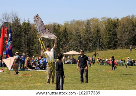 KORTRIGHT CENTER  MAY 06: Man with kite of bird shape at  Four Winds Spring Kite Festival in May 06 2012 in Kortright Center in Ontario, Canada.