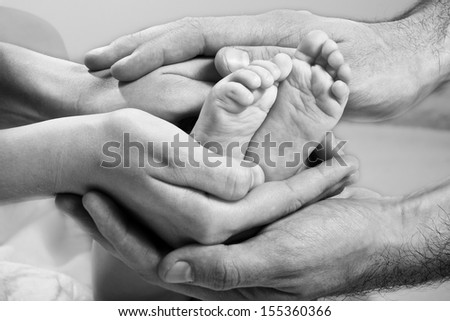 Newborn Baby Feet On Parents Hands