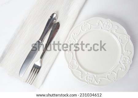 Nice vintage ceramic plate with silver fork and knife on wooden table