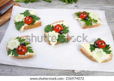 Nice red lady-bird on bread with vegetable on wooden board with napkin