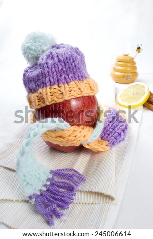 Concept of flu sick person with cap and scarf with healthy tea, fruit and vegetable