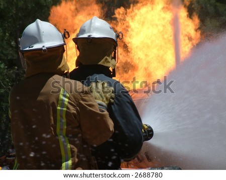 Emergency Fire Fighter Crew work as a team while fighting a huge blaze. Featuring a gas tank burning out of control in a bush fire after a 911 - 000 call with fire hose extinguishing.