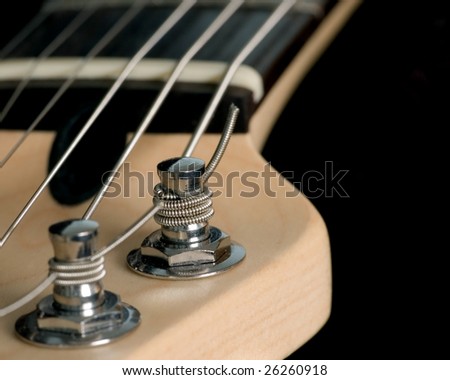 A macro closeup shot of an electric guitar head stock with string tuning pegs