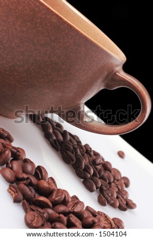 large brown coffee cup with blackbackground on white table with spilt coffee beans