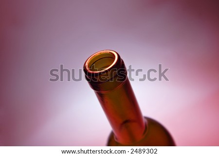 opened bottle of red wine on red ambient background