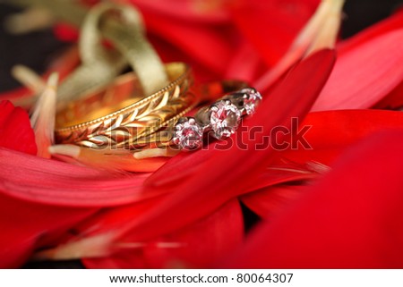 Diamond engagement ring with gold wedding band amongst red petals