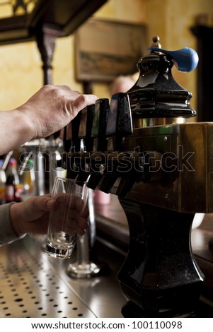 Cropped view of the hands of a barman dispensing drought beer from generator
