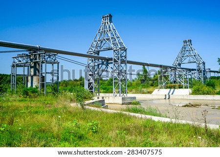 Gas pipe lines that laid through muddy river and green forest in summer scenery, Romania.