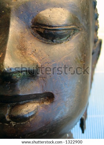 A bronzed sculpture of Buddhaâ€™s face.