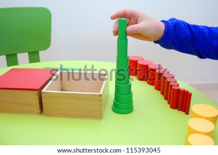 Child hand building tower made of montessori educational materials
