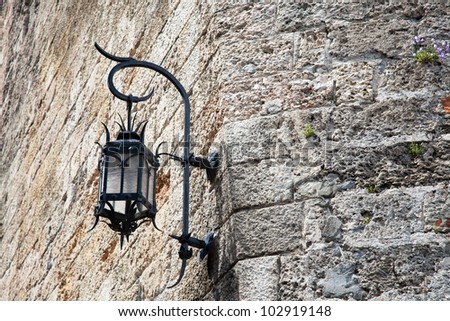 Old outdoor street lamp on stone wall near the palace in Monaco.