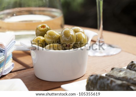 Green olives stuffed with red pimento in small white bowl.