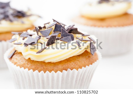 Vanilla cupcake with yellow frosting and chocolate flakes.