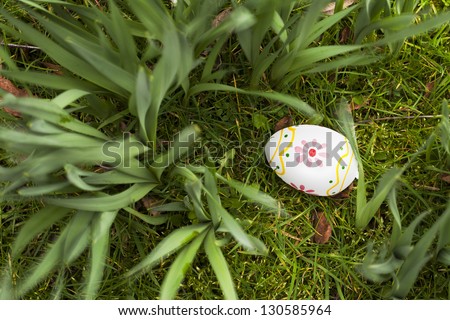 Painted Easter egg hidden in the grass and bulbs.