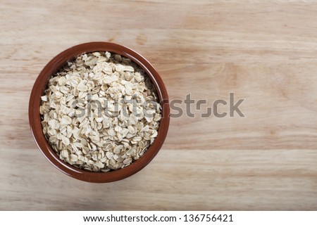 Bowl of rolled oats on wooden surface