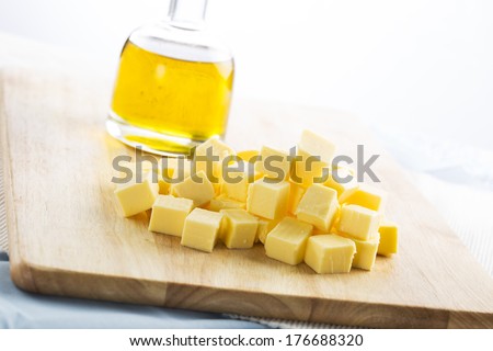 Butter pieces (cubes) on a cutting board, with bottle of vegetable oil in the background