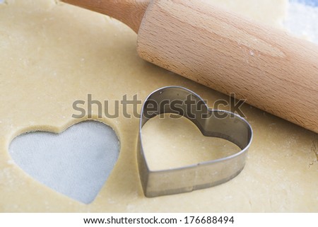 Dough rolled out with heart shape cut out, and heart shaped cookie cutter